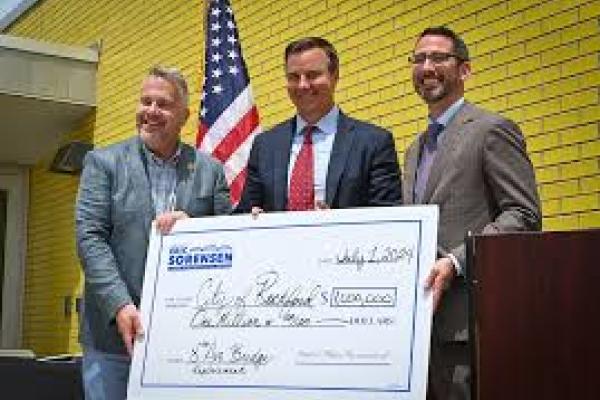 Rep Sorensen holds a large check of federal funds.
