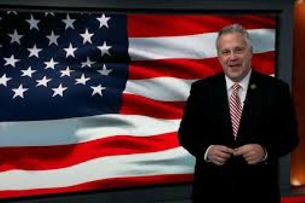 Rep Sorensen stands in front of an American flag.