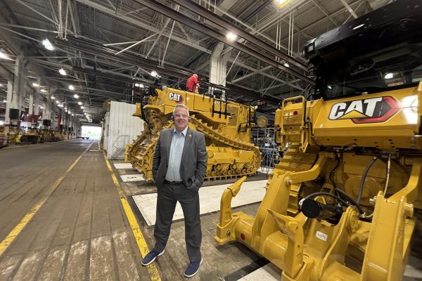 Congressman Sorensen in front of Caterpillar machines.