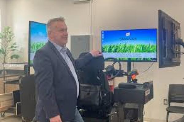 Rep. Sorensen stands with a farming simulator