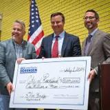 Rep Sorensen holds a large check of federal funds.
