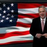 Rep Sorensen stands in front of an American flag.