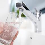 Person filling a cup of water at a faucet