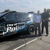 Congressman Eric Sorensen and local law enforcement officer stand next to police vehicle