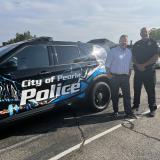 Congressman Eric Sorensen and police officer stand in front of department vehicle