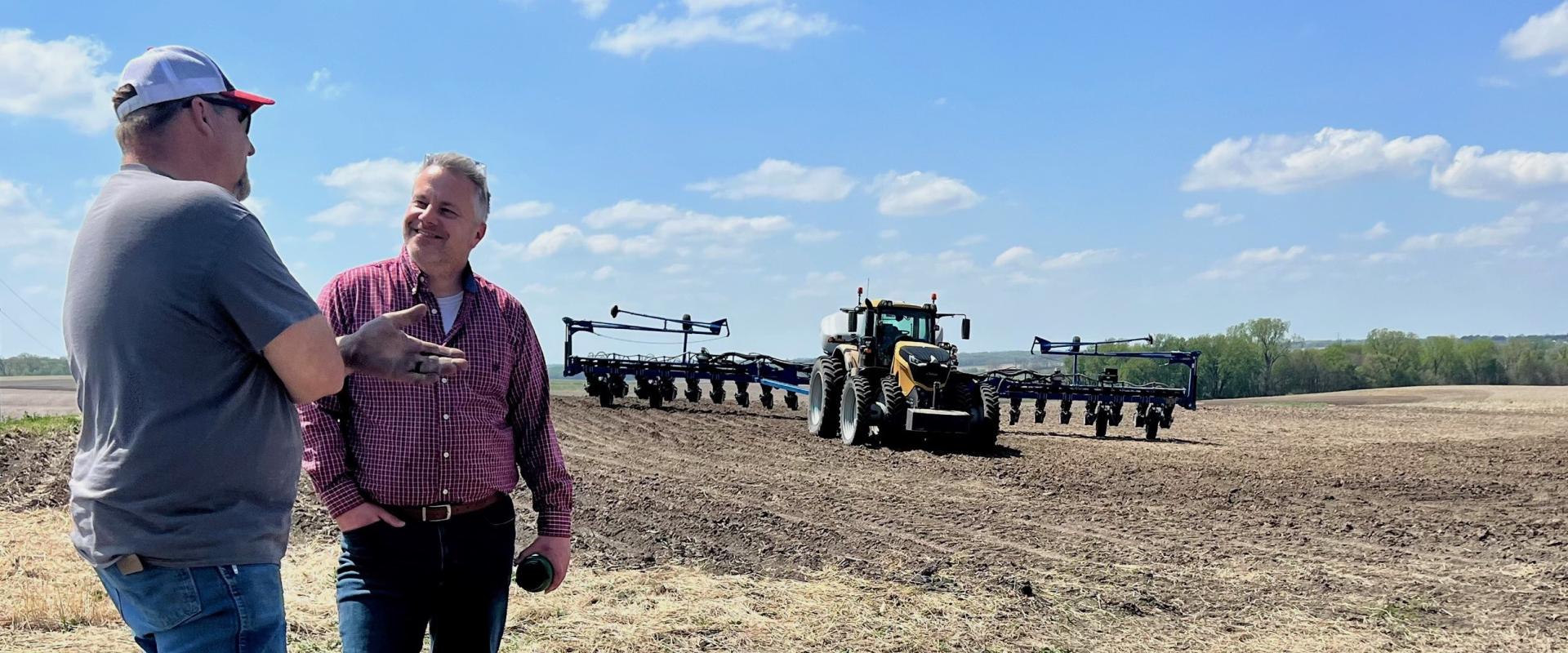 Congressman Sorensen speaks to farmer with farm and tractor in the background.